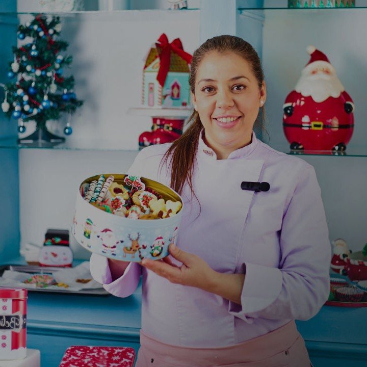Chef pastelera sonriendo con una lata de galletas navideñas en las manos
